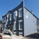 Painters on ladders repainting a townhouse exterior in navy